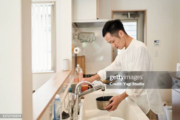 mid adult man preparing food in the kitchen - man housework stock pictures, royalty-free photos & images