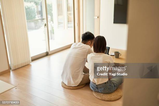 asian couple using a digital tablet in living room. - the japanese wife stock pictures, royalty-free photos & images