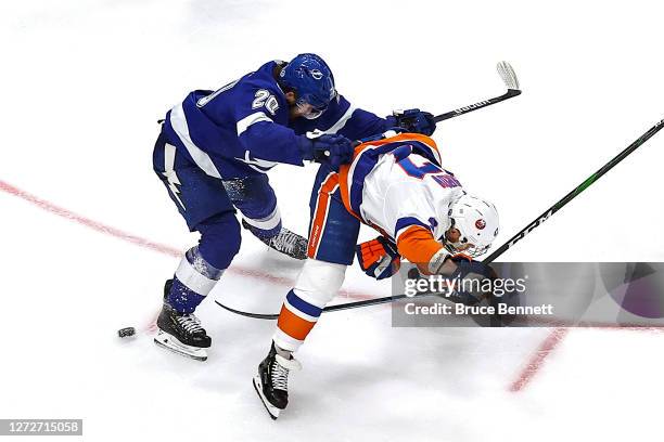 Leo Komarov of the New York Islanders attempts a shot through his legs against Blake Coleman of the Tampa Bay Lightning during the first overtime...