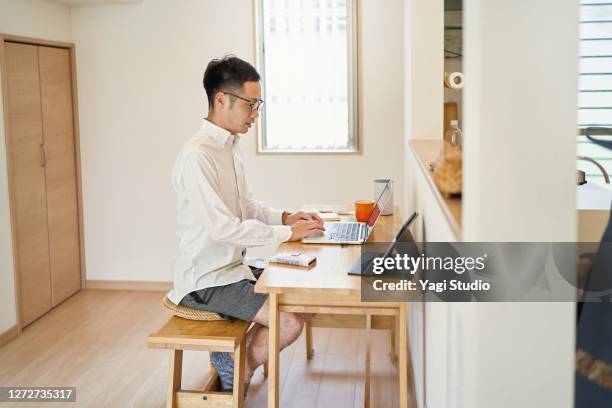 man working from home in a makeshift office in the living room - mens shorts stock pictures, royalty-free photos & images