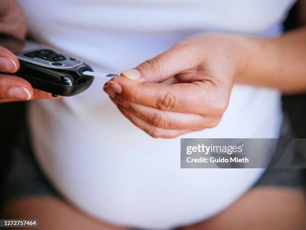 pregnant woman is using a glucometer at home. - diabetes gestacional fotografías e imágenes de stock