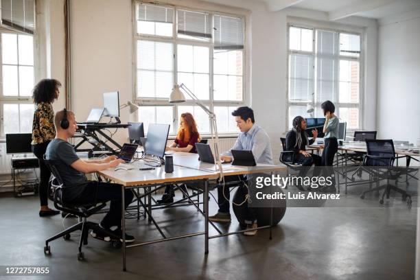 business people working in a busy open plan office - open laptop on desk stock-fotos und bilder