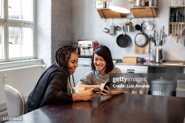 colleagues using phone and smiling in office - südostasiatischer abstammung stock-fotos und bilder