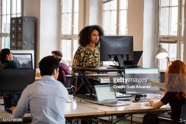woman working on computer at ergonomic standing desk in office - design laptop woman stock-fotos und bilder