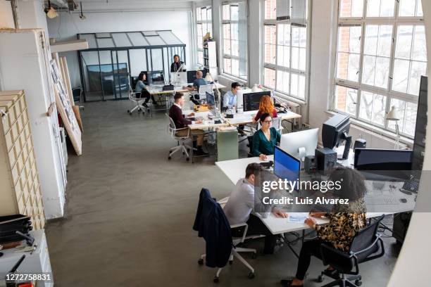 large office space with people working - oficina de plan abierto fotografías e imágenes de stock