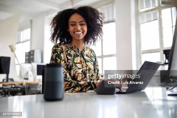 woman using smart speaker while working in office - woman business desk front laptop office fotografías e imágenes de stock