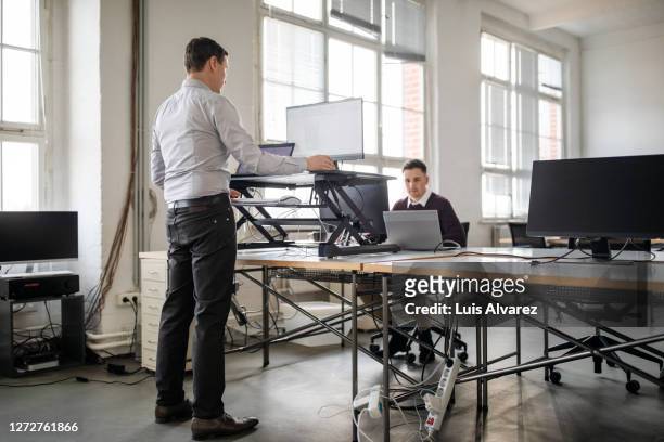 man working on computer at ergonomic standing desk in office - ergonomie stock-fotos und bilder