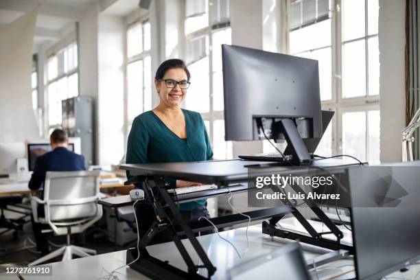 woman working at a standing desk in a modern office - ergonomie stockfoto's en -beelden