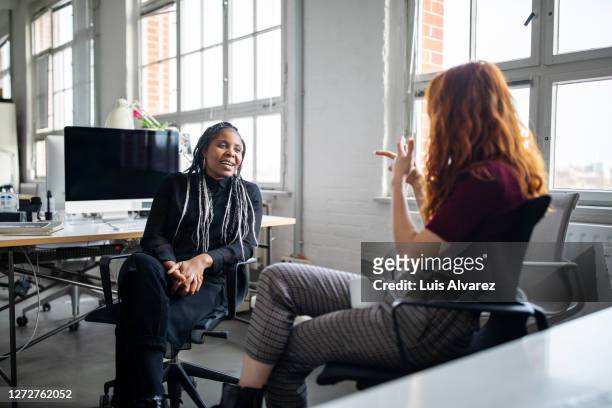 female coworkers discussing work at their desk - long table stock pictures, royalty-free photos & images