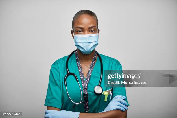 african american doctor/nurse with arms crossed against white background - face mask coronavirus photos et images de collection
