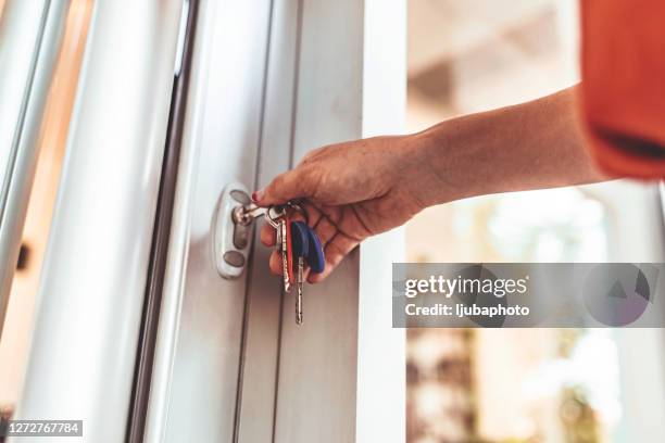 jonge vrouw die de voordeur van haar flatgebouw opent - locking stockfoto's en -beelden