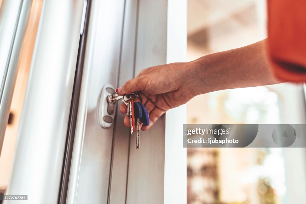 Young woman opening the front door of her apartment building