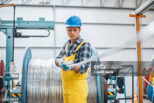 porträt eines jungen geschäftsmannes, der mit kabelwalze in der fabrik arbeitet - copper coil stock-fotos und bilder