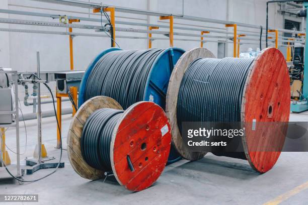 grandes bobines en bois avec le fil de câble contre l’entrepôt d’usine extérieur - cable photos et images de collection