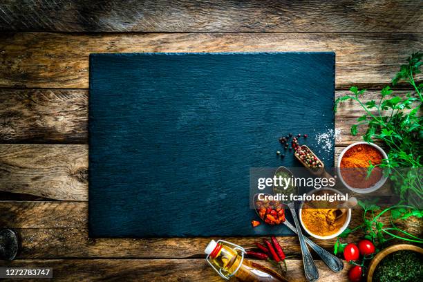 fondo de cocina: especias multicolores, hierbas y verduras sobre mesa de madera rústica. copiar espacio - tabla de cortar fotografías e imágenes de stock