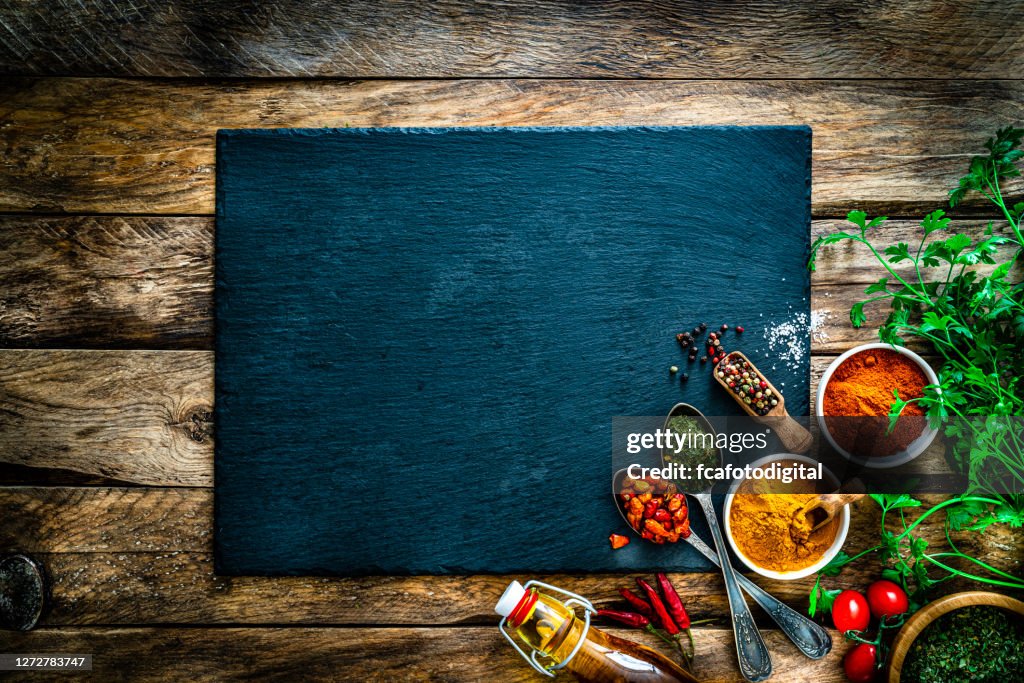 Cooking background: multi colored spices, herbs and vegetables on rustic wooden table. Copy space