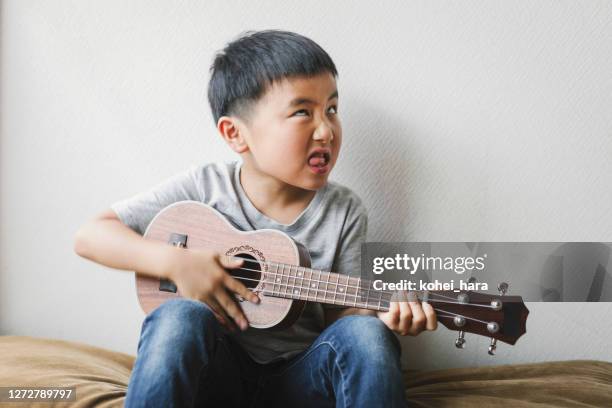 boy playing ukulele at home - tuning stock pictures, royalty-free photos & images