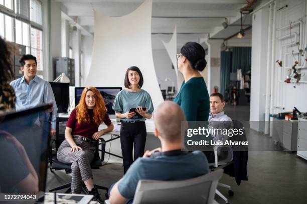female sharing her ideas in a staff meeting - réunion du personnel photos et images de collection