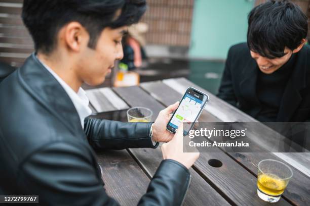 young japanese man using smart phone for online trading - over the shoulder view stock pictures, royalty-free photos & images