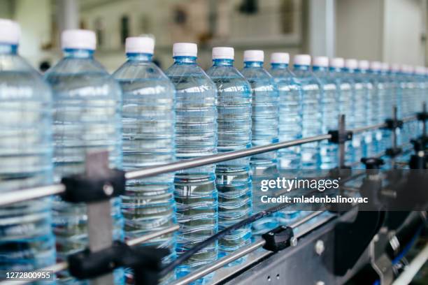 interiores industriales o interiores y maquinaria. línea de fábrica para embotellado de agua pura de manantial en botellas y botes. - bottle water fotografías e imágenes de stock