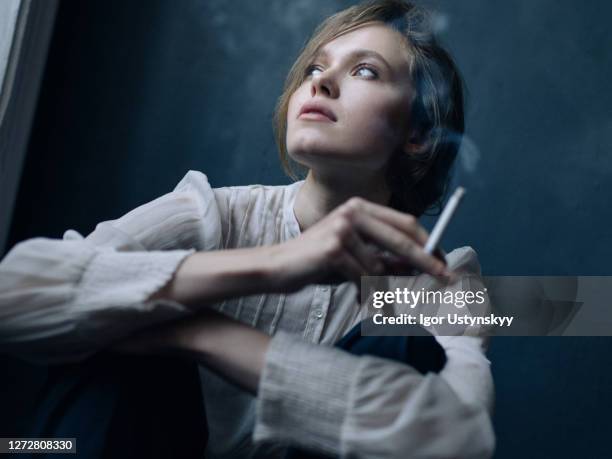 young beautiful woman smoking indoors - studio shot lonely woman stock pictures, royalty-free photos & images