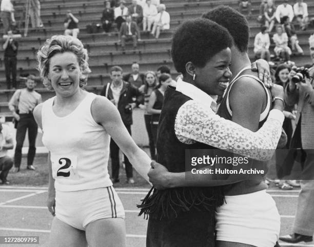 South African-born British runner Lillian Board congratulates the race-winner, Jamaican-born British runner Marilyn Neufville, who is embraced by a...