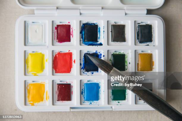 palette with multi color paints and brush on white background, top view - gouache stockfoto's en -beelden