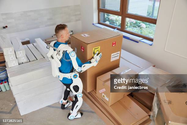 proffesional mover in exoskeleton. carrying heavy boxes into flat - exoskeleton stock pictures, royalty-free photos & images