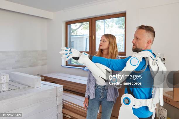 jeune propriétaire d’appartement planification intérieur avec déménageur proffesional dans exosquelette. utilisation d’une tablette - exosquelette photos et images de collection