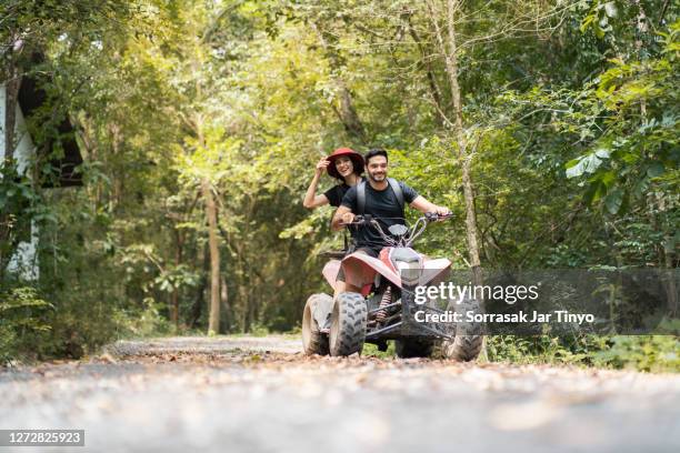 rear view of a couple driving a quad bike at the adventure outdoor park - atv trail stockfoto's en -beelden