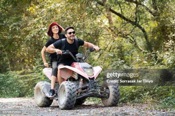 a couple driving a quad bike at the adventure outdoor park - quadbike ストックフォトと画像