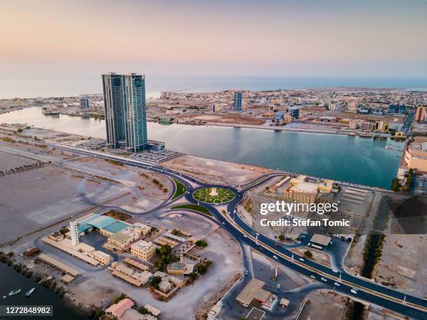 ras al khaimah emirate cityscape skyline rising over the mangroves and the creek in the united arab emirates at sunset - ras al khaimah stock pictures, royalty-free photos & images