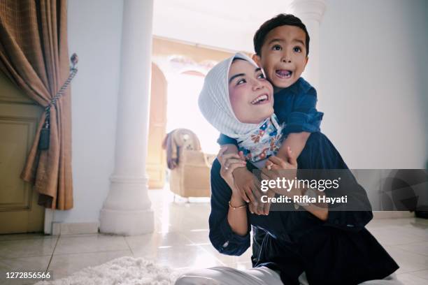 hermosa mamá asiática trabajando desde casa y cuidando de sus hijos - archipiélago malayo fotografías e imágenes de stock