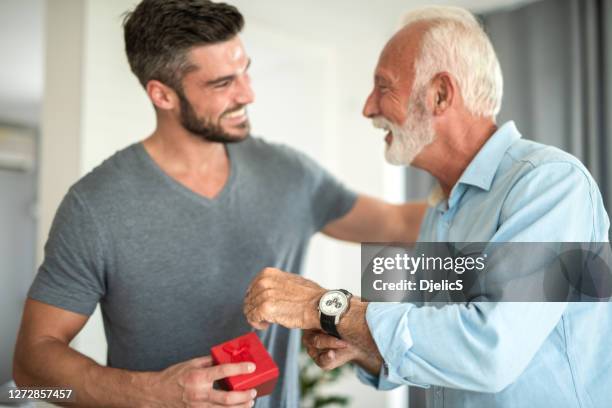 gelukkige jonge mens die een horloge aan zijn vader geeft. - tijdmeter stockfoto's en -beelden