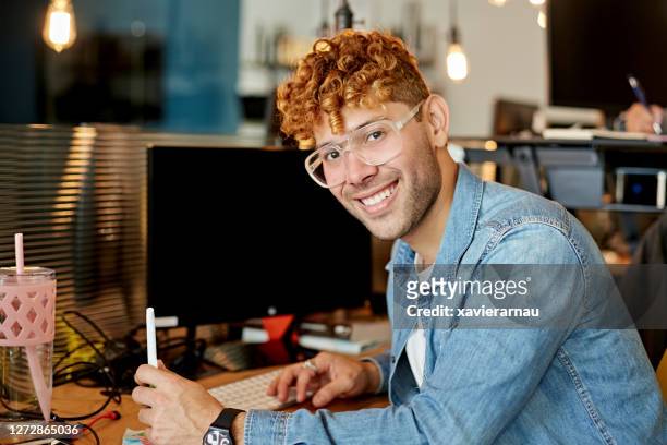 retrato de joven freelancer hispano en la oficina de coworking - corte de pelo con media cabeza rapada fotografías e imágenes de stock