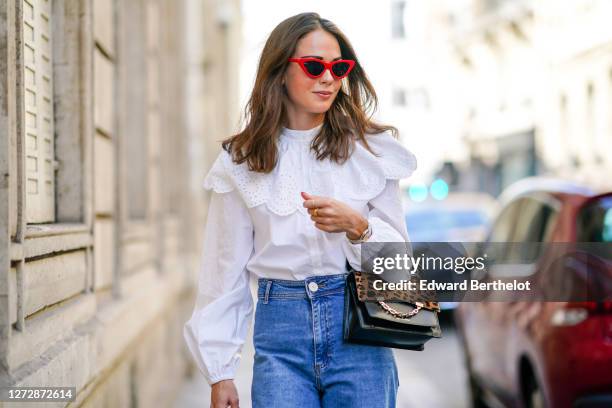 Therese Hellström wears red Celine sunglasses, a white shirt / blouse from H&M with large ruffled collar, a black leather Karl Lagerfeld bag with a...