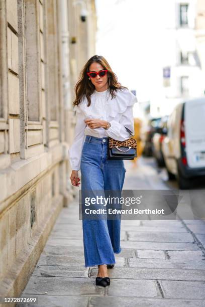 Therese Hellström wears red Celine sunglasses, a white shirt / blouse from H&M with large ruffled collar, a black leather Karl Lagerfeld bag with a...