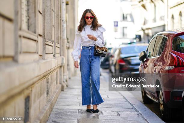 Therese Hellström wears red Celine sunglasses, a white shirt / blouse from H&M with large ruffled collar, a black leather Karl Lagerfeld bag with a...