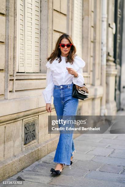 Therese Hellström wears red Celine sunglasses, a white shirt / blouse from H&M with large ruffled collar, a black leather Karl Lagerfeld bag with a...