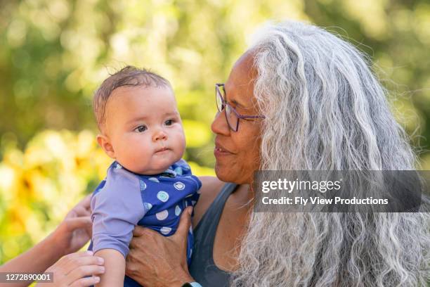 de baby in zwempak snuggles oma op een hete de zomerdag - hawaiiaanse etniciteit stockfoto's en -beelden