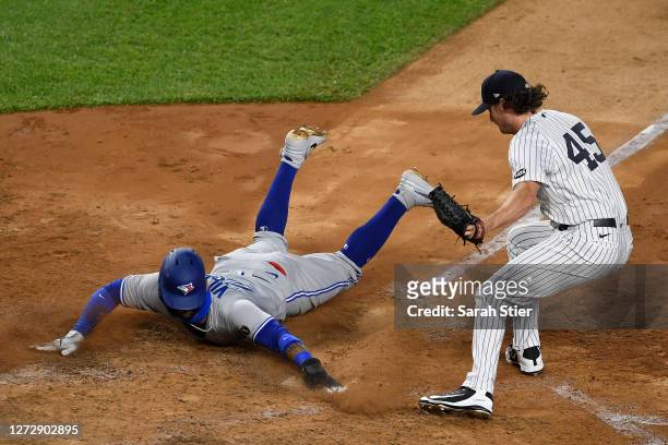Jonathan Villar of the Toronto Blue Jays slides into home ahead of the tag from pitcher Gerrit Cole of the New York Yankees during the sixth inning...