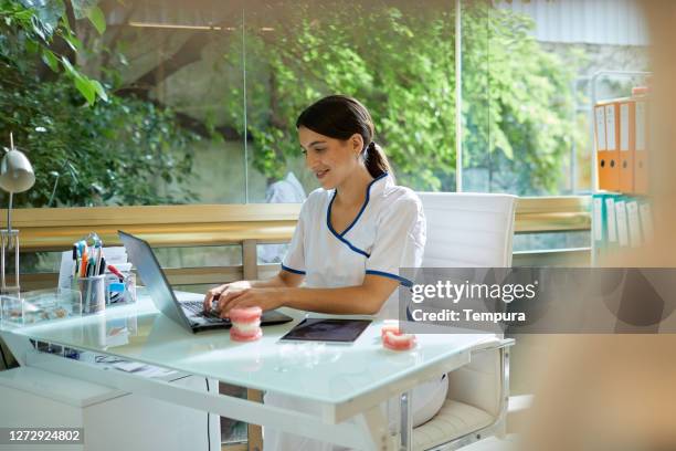 a female dentist working on a laptop. - dentists stock pictures, royalty-free photos & images