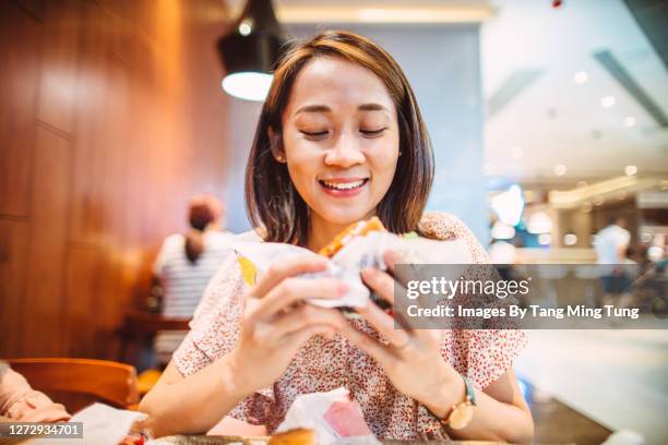 young pretty asian woman enjoying freshly made delicious burger in restaurant - fat asian woman 個照片及圖片檔