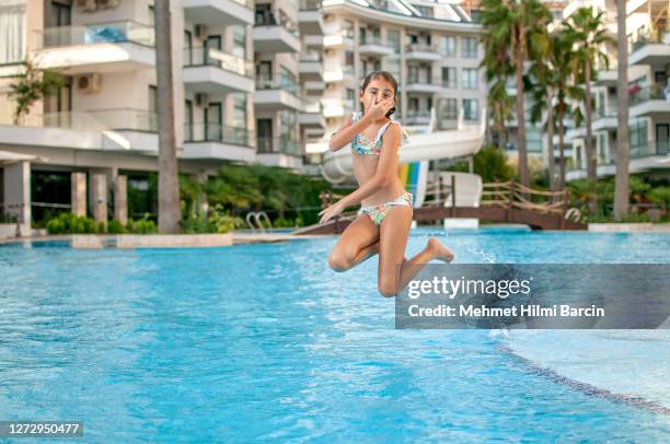happy child girl enjoying in the pool - young girl jumping into swimming pool stock pictures, royalty-free photos & images