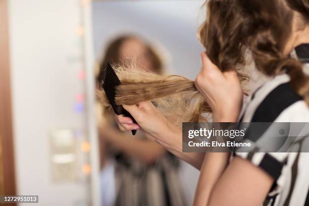 teenage girl using comb to untangle dry, knotted hair - dry hair stock-fotos und bilder