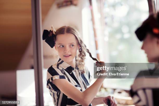 teenage girl unrolling hair curls from socks used as heatless curlers - hair curlers stockfoto's en -beelden