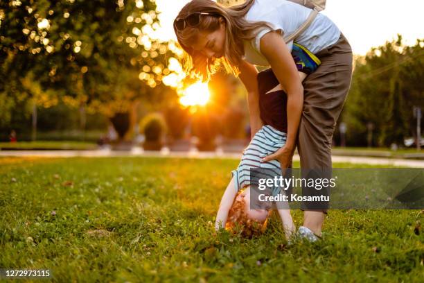 lovely mother trying to help his ginger son to do a handstand - boy handstand stock pictures, royalty-free photos & images