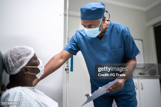 nurse talking and doing a emotional support to a female senior patient at hospital - wearing face mask - surgery preparation stock pictures, royalty-free photos & images