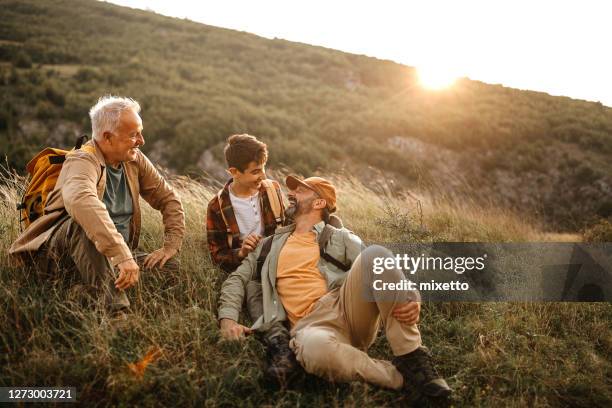 felices tres generaciones hombres relajarse en el tour de senderismo - padre e hijo fotografías e imágenes de stock