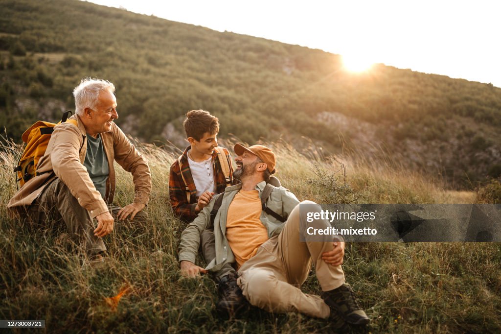 Happy three generations males relaxing on hiking tour